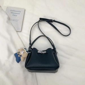 Detail of black lychee grain bucket bag with silver clasp and cute teddy bear charm