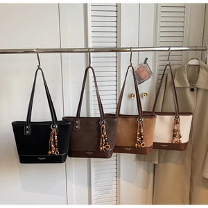 Detail of minimalist tote bags in four colors with stylish beaded tassel pendants