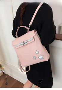 Close-up of pink casual backpack featuring silver star patches and ribbon bow details
