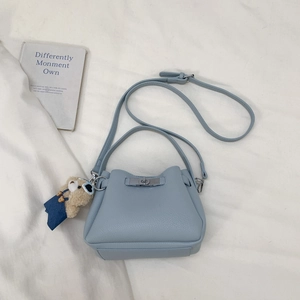 Close-up of light blue pebble grain bucket bag with silver twist lock and bear charm