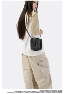 Seitenansicht einer schwarzen Crossbody-Tasche mit Lychee-Lederstruktur an einem Model