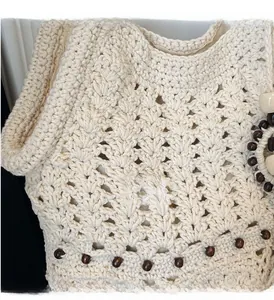 Détail du sac cabas en tricot crème avec motifs ajourés et perles en bois marron