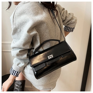 Close-up of black patent leather handbag with silver twist lock and slim shoulder strap