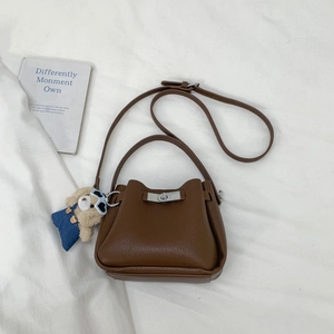 Detail of a brown leather bucket bag with silver twist lock and cute plush bear charm