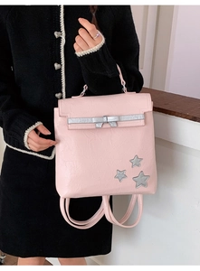 Detail of pink leather backpack with silver bow and stars held by a model