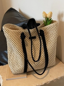 Large beige woven straw tote bag with black rope handles and hollow mesh pattern