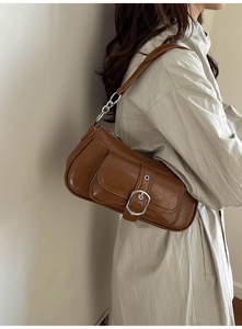 Detailed side view of vintage brown leather underarm bag with silver chain and metal buckle