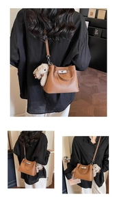 Detailed view of brown lychee grain leather bucket bag with silver lock and plush bunny charm