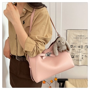Detail view of pink lychee leather bucket bag with cute rabbit charm and silver metal buckle