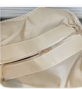 Détail du sac tissé blanc crème montrant la doublure en coton et le zip doré en métal
