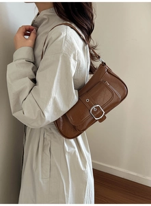 Close-up of retro brown leather armpit bag with metal buckle flap pocket for women