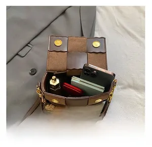 Detail showing the large interior capacity of this woven leather crossbody bag with items