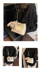 Detail of off-white lychee grain leather bucket bag with silver lock and plush bunny charm