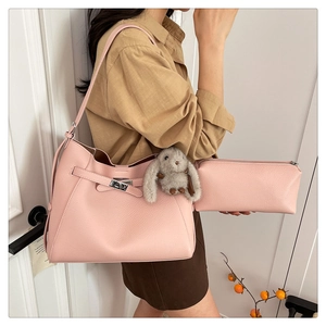 Detail of pink lychee leather tote bag featuring a metal buckle and plush bunny charm