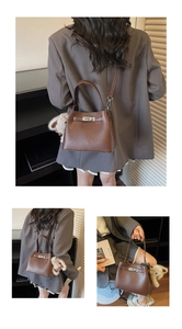 Detail view of dark brown pebbled leather bucket bag with metal twist lock and plush charm