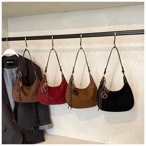Close-up of suede hobo bags in assorted vintage colors with decorative pendants