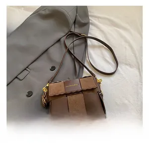 Detail of brown leather messenger bag with checkerboard texture and plush charm