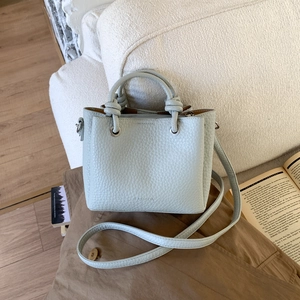 Dettaglio della borsa in pelle azzurra con motivo litchi, manico a nodo e logo fashion