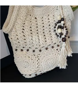 Détail du tissage au crochet et pompons en bois sur un sac de plage beige d'été