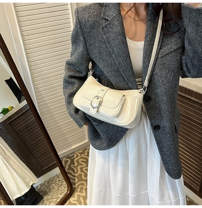 Detail of cream white glossy leather crossbody bag with buckle pocket and zipper closure