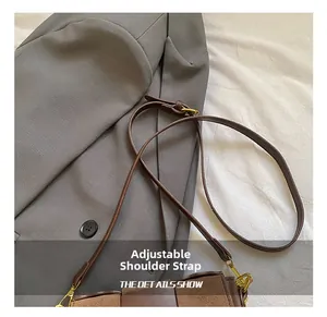 Detail of adjustable brown leather shoulder strap with gold metal buckle and hardware