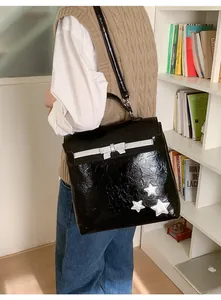Close-up of black pleated texture bag with silver bow and star charms for women