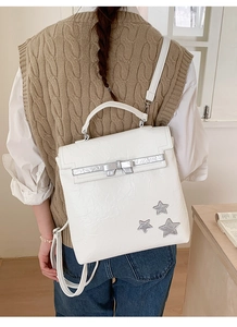 Detail of white textured backpack with silver bow and star accents on model