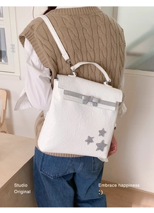 Detail of white pleated PU backpack with silver stars and bow on a female model