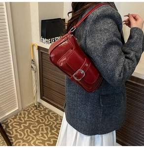 Detail of dark red glossy shoulder bag featuring silver buckle and vintage flap pocket