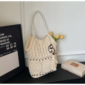 Détails du tissage du sac cabas beige au crochet avec perles en bois et pompon