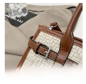 Detail shot of beige woven fabric, caramel leather strap, and silver metal buckle