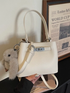 Minimalist beige leather bucket bag with silver clasp and plush rabbit charm