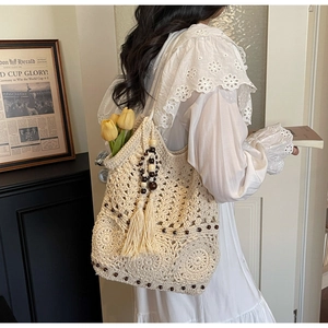 Détail d'un sac cabas au crochet beige avec motifs floraux ajourés et perles en bois