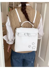 Detail of white leather backpack featuring silver bow decoration and star patches