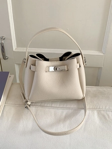 Chic beige bucket bag in lychee leather featuring a silver metal lock and top handle