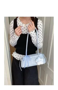 Detail of light blue underarm bag with ribbon bow and plush star pendant on a model