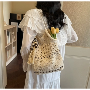 Détail d'un sac tissé avec motifs crochetés ajourés et un pompon à perles en bois