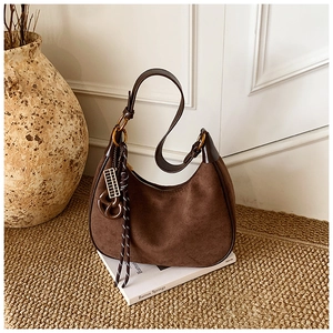 Detailed macro view of dark brown suede hobo bag with braided lanyard on a rug