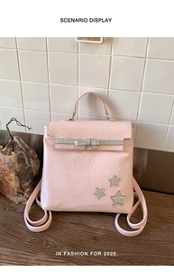Pink textured backpack with silver bow ribbon and star patches on wood surface