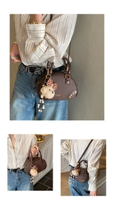 Detail of dark brown boston bag with lychee texture leather and bear charm pendant