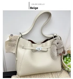 Detail of beige pebbled leather bucket bag with silver lock and plush rabbit charm