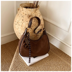 Close-up of brown suede half-moon shoulder bag with leather trim and gold hardware details
