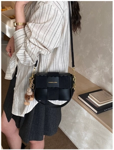 Detail of black woven leather crossbody bag with a plush bear charm and adjustable strap