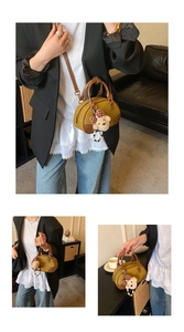 Detail view of mustard yellow bowling bag with brown ring handles and plush bear charm