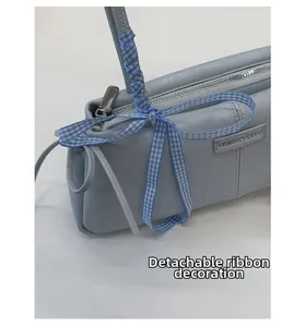 Close-up of light blue shoulder bag with FASHION & BAGS logo and blue checkered ribbon