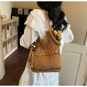 Détail du sac cabas en paille tressée avec motifs floraux au crochet et charms à franges