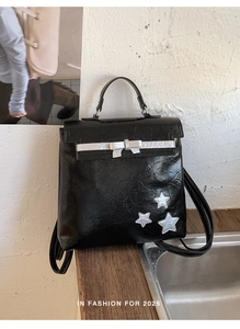 Detail of glossy black backpack with silver star appliques and metallic bow buckle