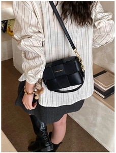 Detail of woven black leather textures and golden logo on retro stylish crossbody bag