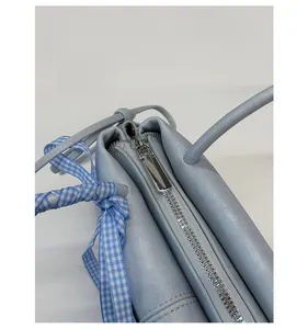 Detail of light blue handbag with smooth silver zipper and blue checkered silk scarf wrap