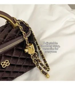 Detail of dark brown velvet quilted bag with golden chain and petal metal base